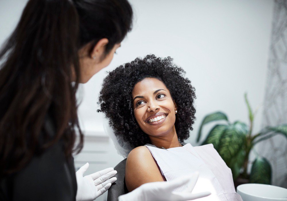 Orthodontics patient model smiling in dental chair receiving an exam