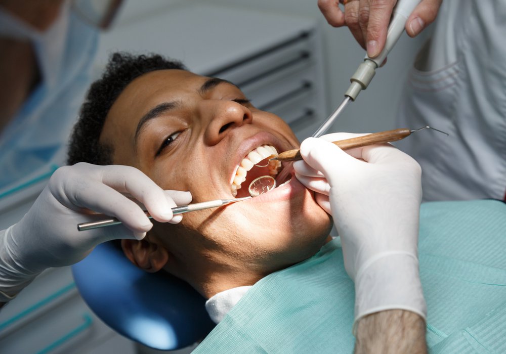 emergency dentist patient model having his teeth worked on laying in a dental chair