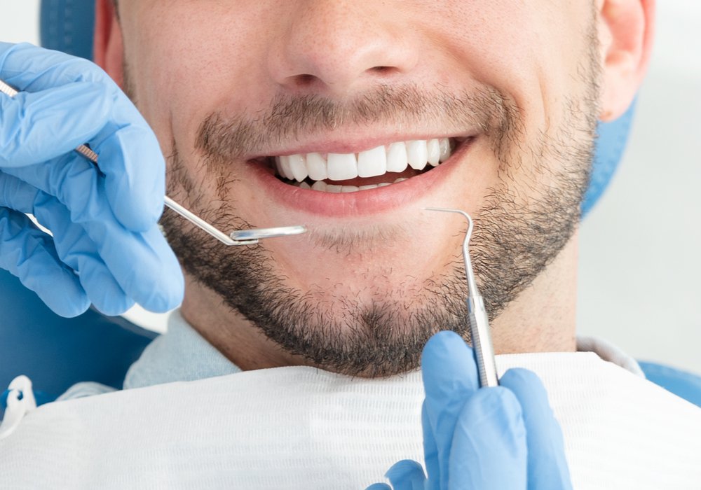 periodontics patient model smiling while getting a teeth cleaning